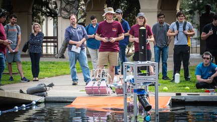 A student is operating a robot going into water during the ME72 Competition