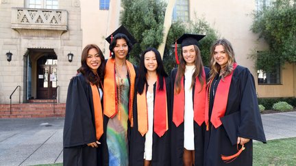 Five students wearing commencement regalia