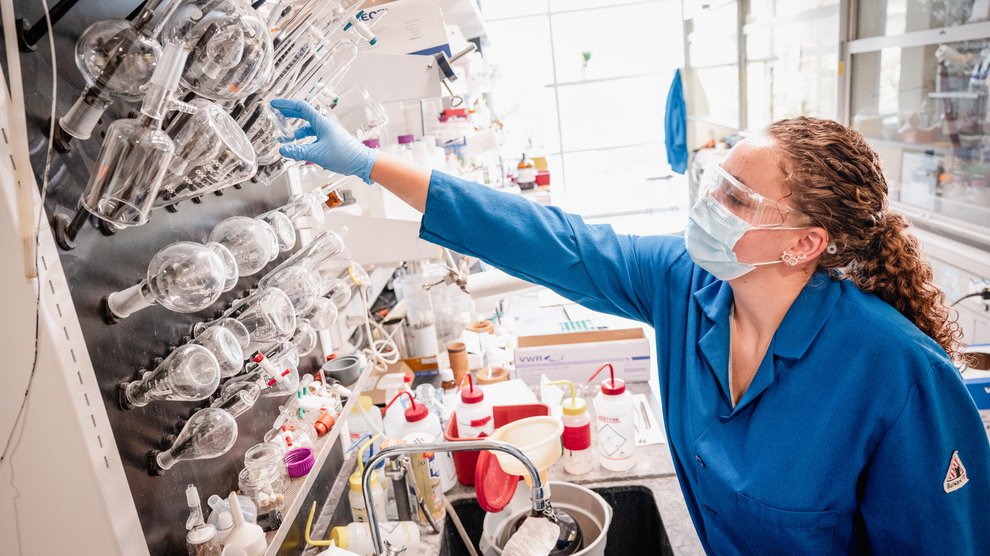 Student in chem lab reaching for beakers.