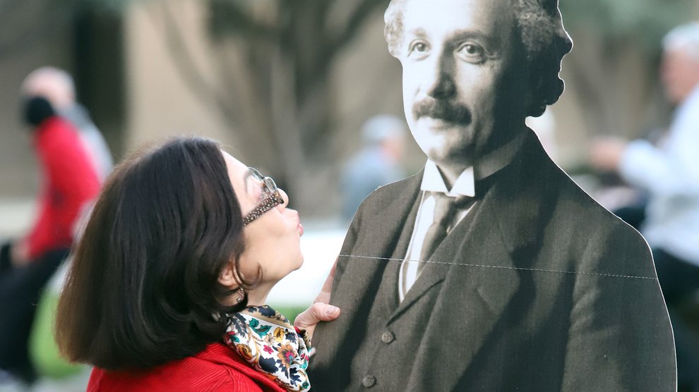 image of woman kissing cardboard cutout of einstein
