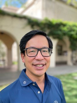 Asian man with glasses wearing a blue polo shirt