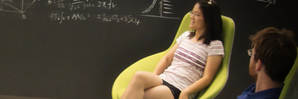 Young woman and young man sitting in green chairs, talking