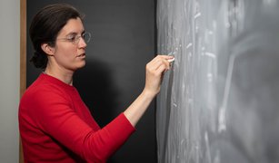 Kathryn Zurek writing on chalkboard