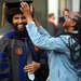 A woman with long dark braids and a denim jacket straightens the mortarboard of a smiling man who is graduating from Caltech