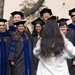 A woman in a white jacket with long dark hair takes a photograph of 12 Caltech graduates