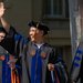 Three Caltech graduates enter their commencement ceremony. One is waving to someone outside the photo's frame.