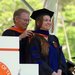 An older man wearing glasses places an orange stole around the neck of a woman who is graduating from Caltech