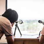 student looking into the sky through a telescope