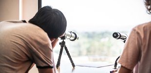 student looking into the sky through a telescope