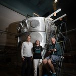 Members of the nEDM team stand in front of their magnetic cryovessel experimental apparatus