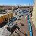 A tracked vehicle making its way through a track set up on a wooden walkway with blue pool noodles outlining the curves of the track.