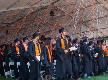 Orange, black, and white confetti falls on Caltech's newest graduates who are wearing their caps and gowns