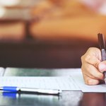 Stock photo of a person's hand writing on a paper at a desk