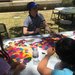 People sit at a table, tiling together brightly colored pieces of a single shape