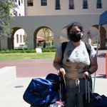 Student Jennifer Rodriguez stands with her luggage in front of the Moore Laboratory of Engineering