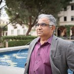 Image of Shri Kulkarni in purple shirt and grey blazer in front of fountain