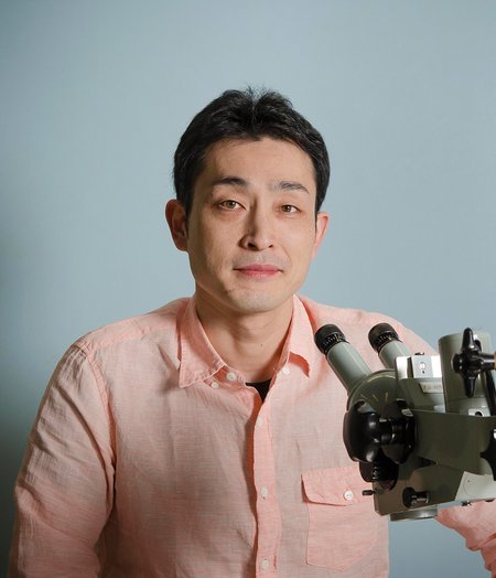 A man sits next to a microscope