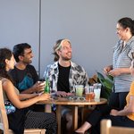 five students sit around a table talking and drinking beverages