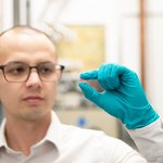 Christopher Simon holds a pink crystal made of lithium holmium yttrium fluoride.