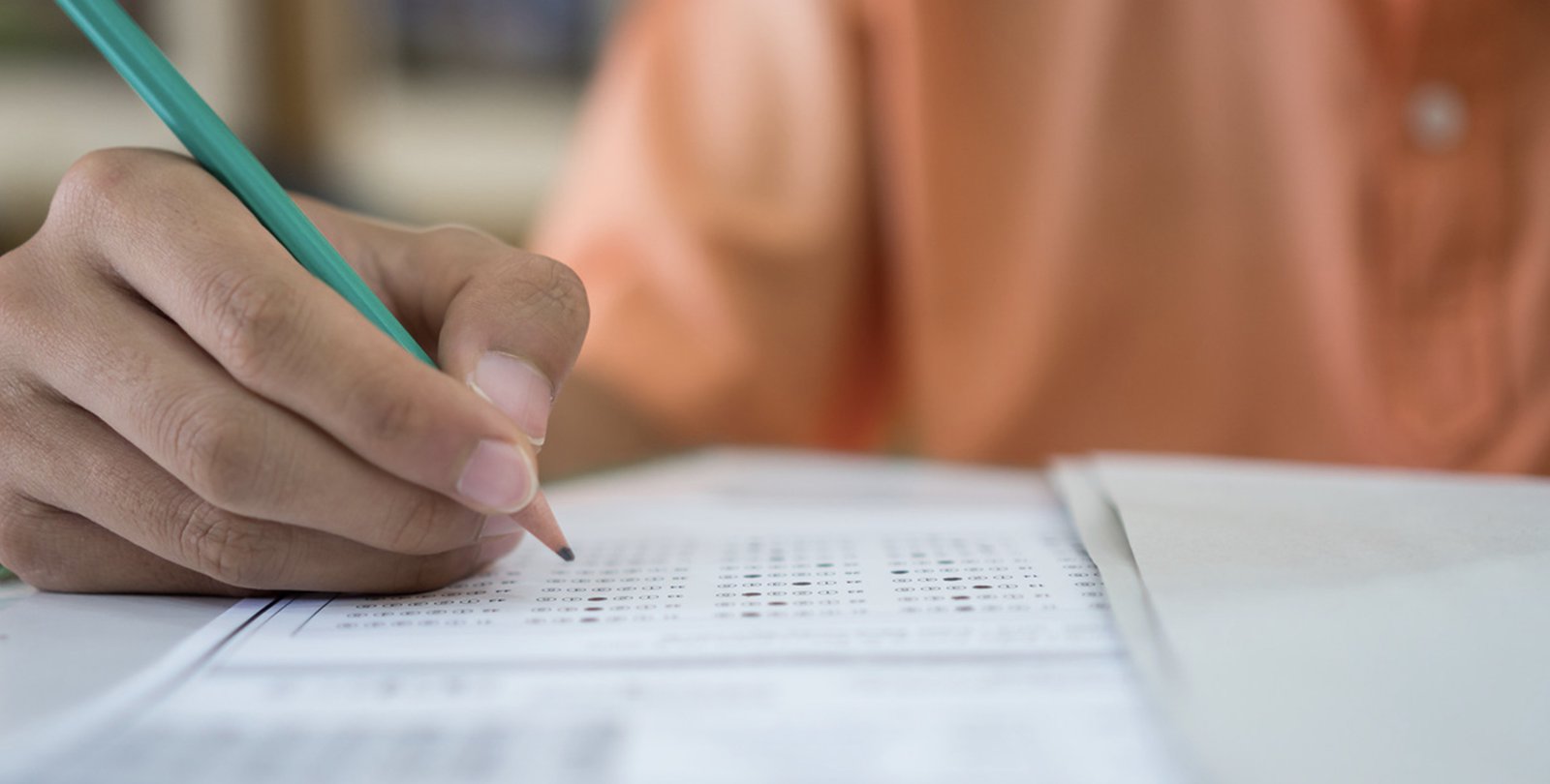 A hand holding pencil fills out a standardized test