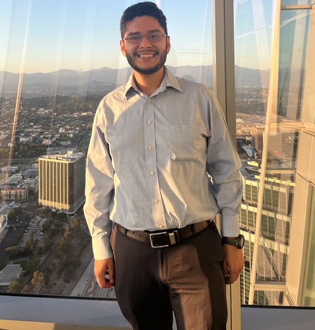 Tony Rodriguez posing inside a tall building with a view outside.