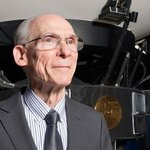 Ed Stone standing in front of a scale-model of the Voyager spacecraft at NASA's Jet Propulsion Laboratory.