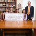 Six Girl Scout Brownies stand with Caltech President Thomas Rosenbaum holding a giant representation of the check they donated