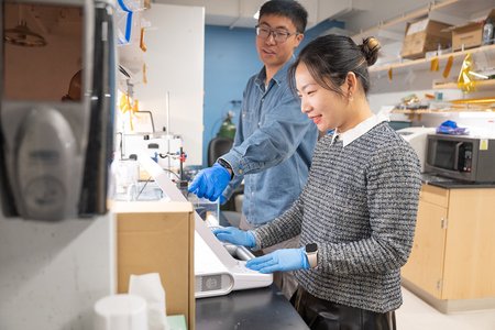 Two graduate students and Professor Wei Gao are shown working in the lab.